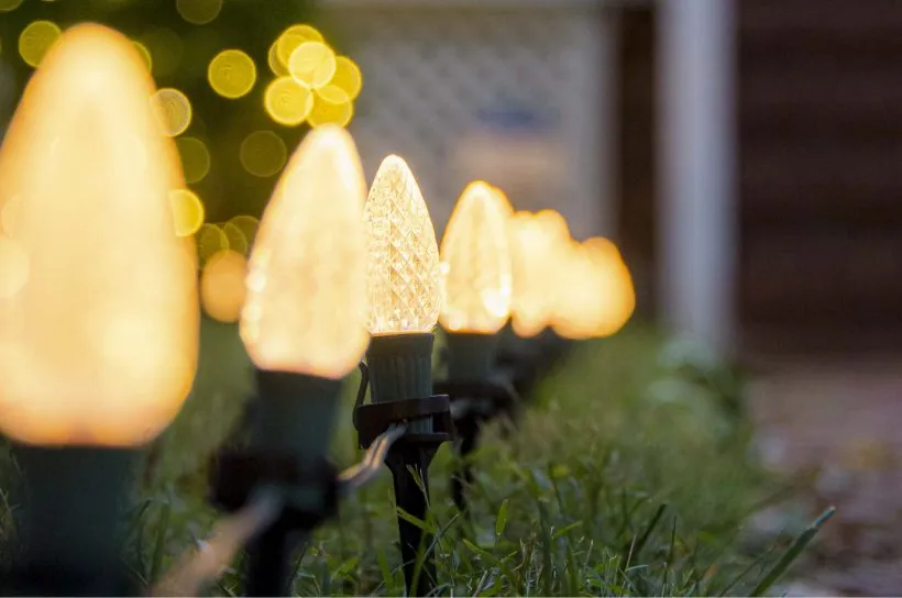 A row of warm white stake lights along a lawn edge