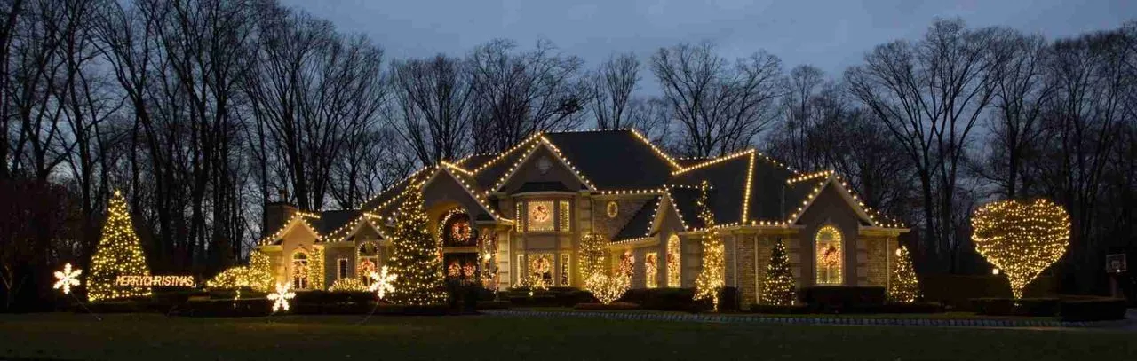 A large home lit entirely in warm white with a lit Merry Christmas sign