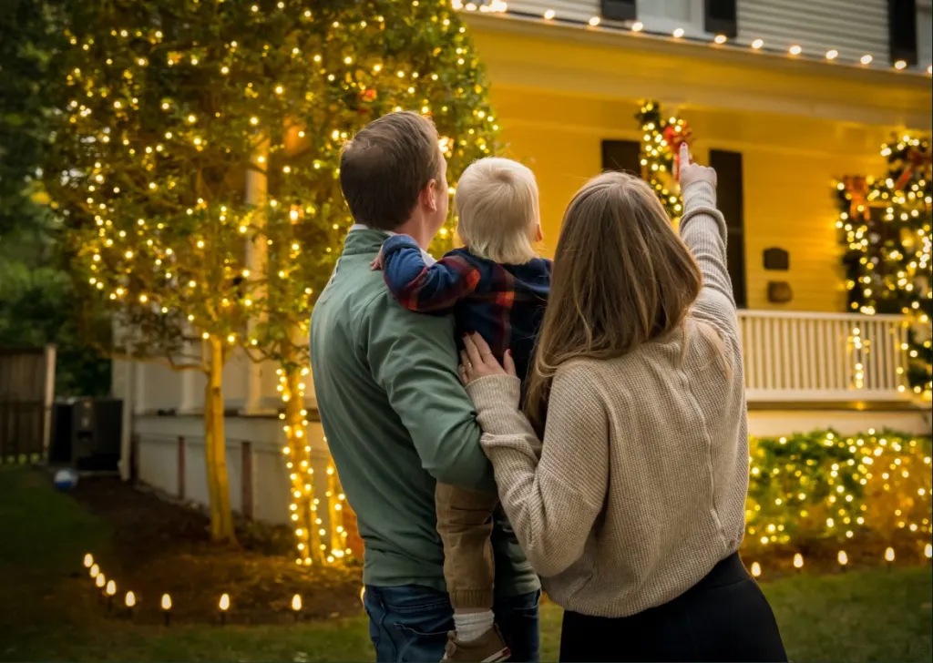 A family looking up at their home lit for the season