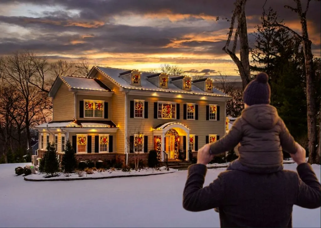 A parent and child looking at a colonial home lit at sunset
