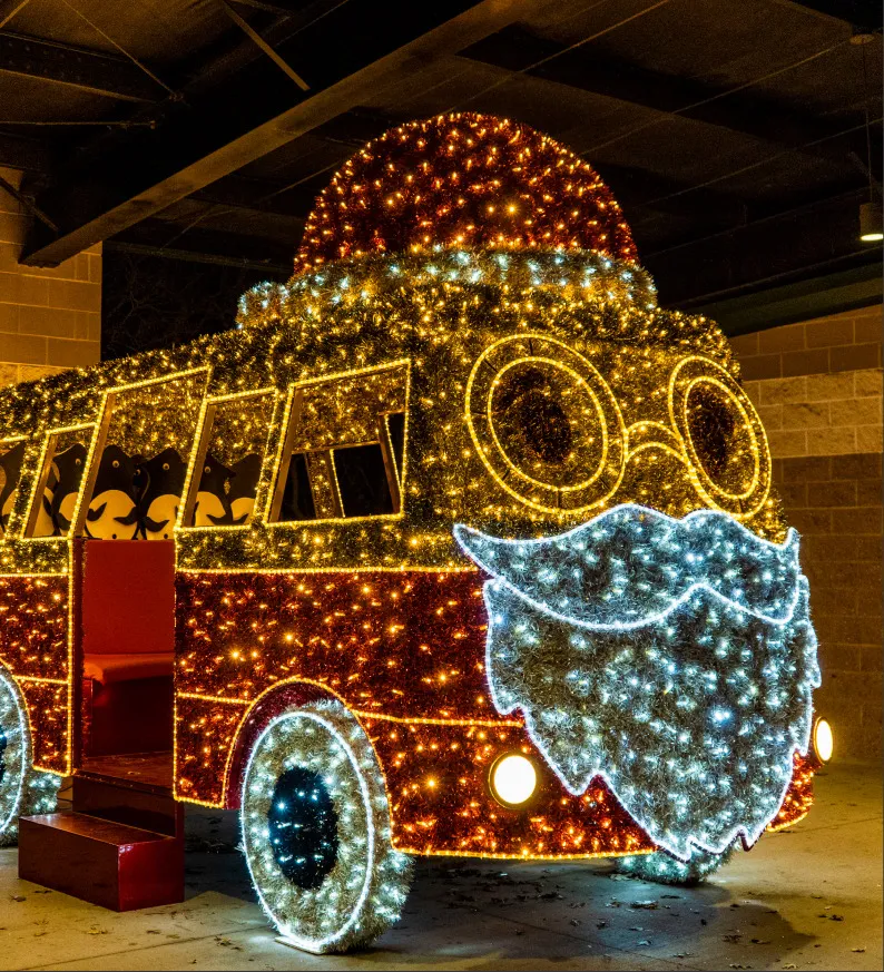 A bus-shaped light sculpture with a lit Santa face