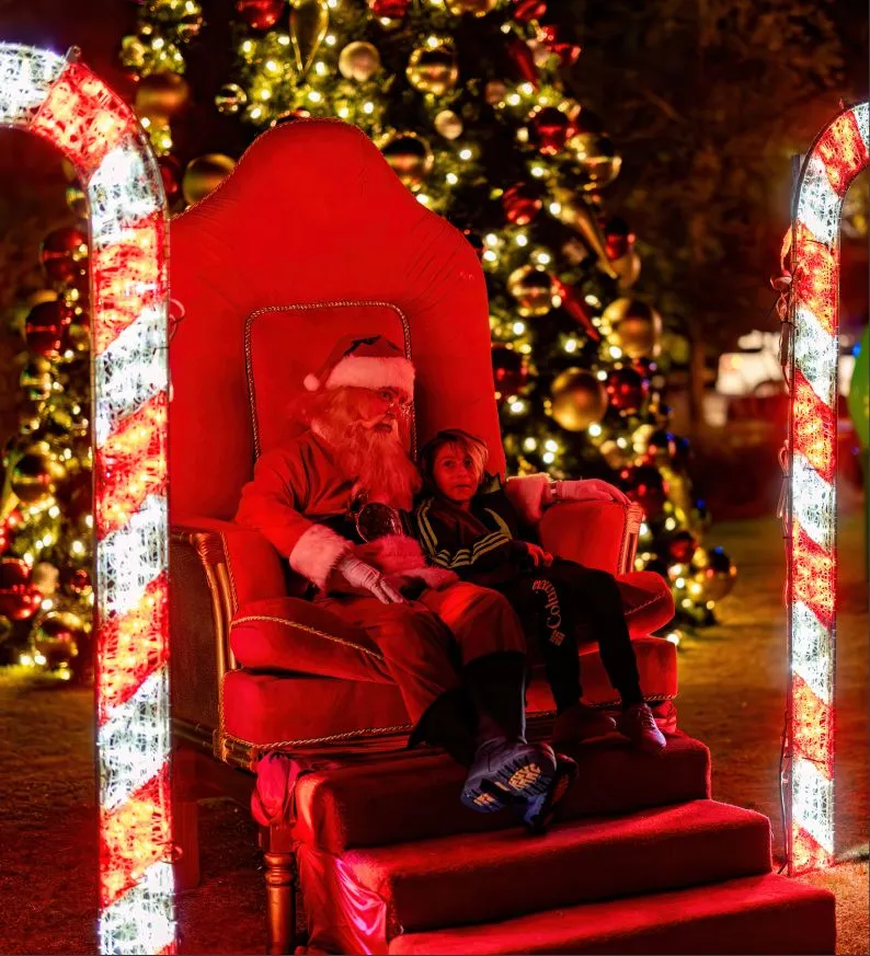 A child meeting Santa on a lit throne between candy-cane arches