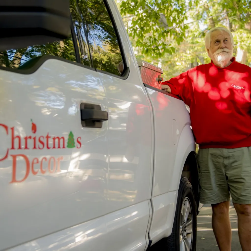 A decorator beside a Christmas Decor service truck