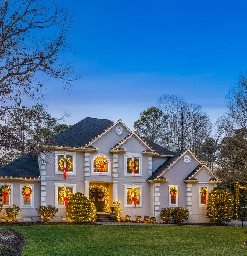 Residential holiday light installation on roofline and landscaping