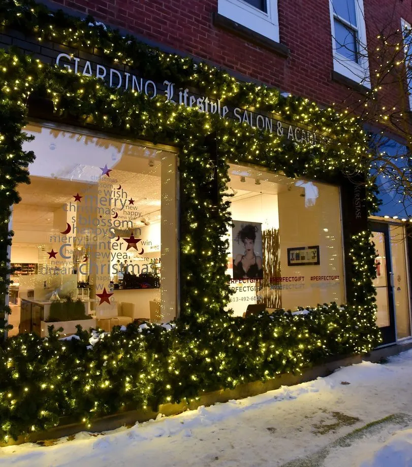 Lit garland framing a salon storefront on a snowy street