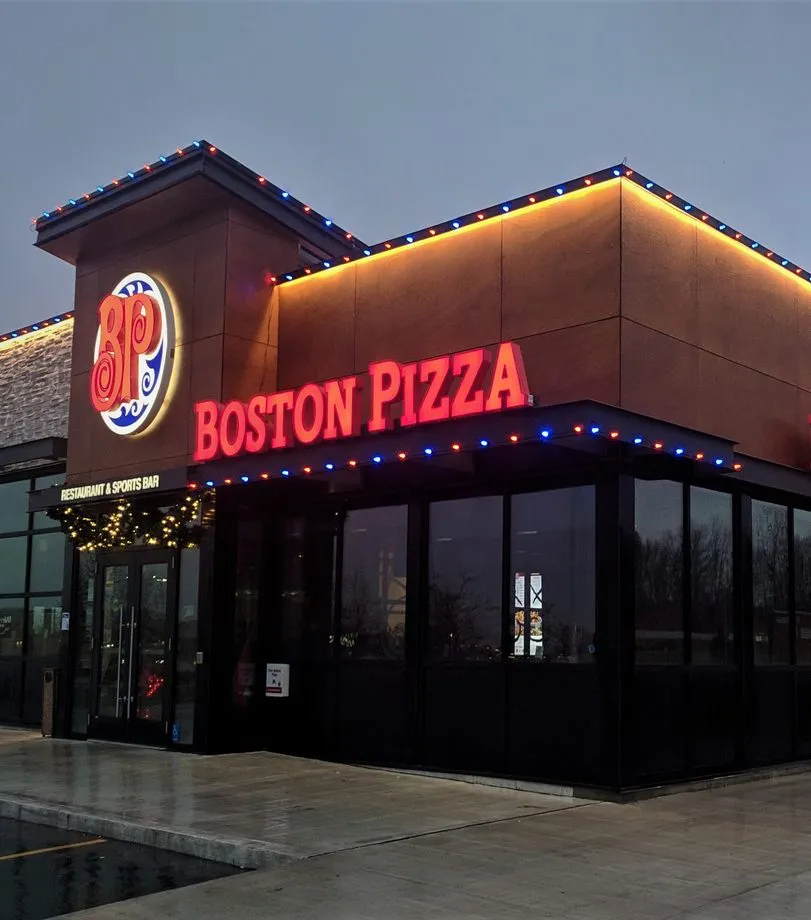 A restaurant roofline and sign picked out in red, blue and warm white