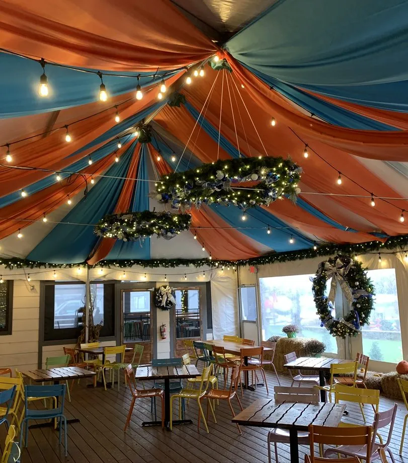 Lit wreath chandeliers under a draped event canopy