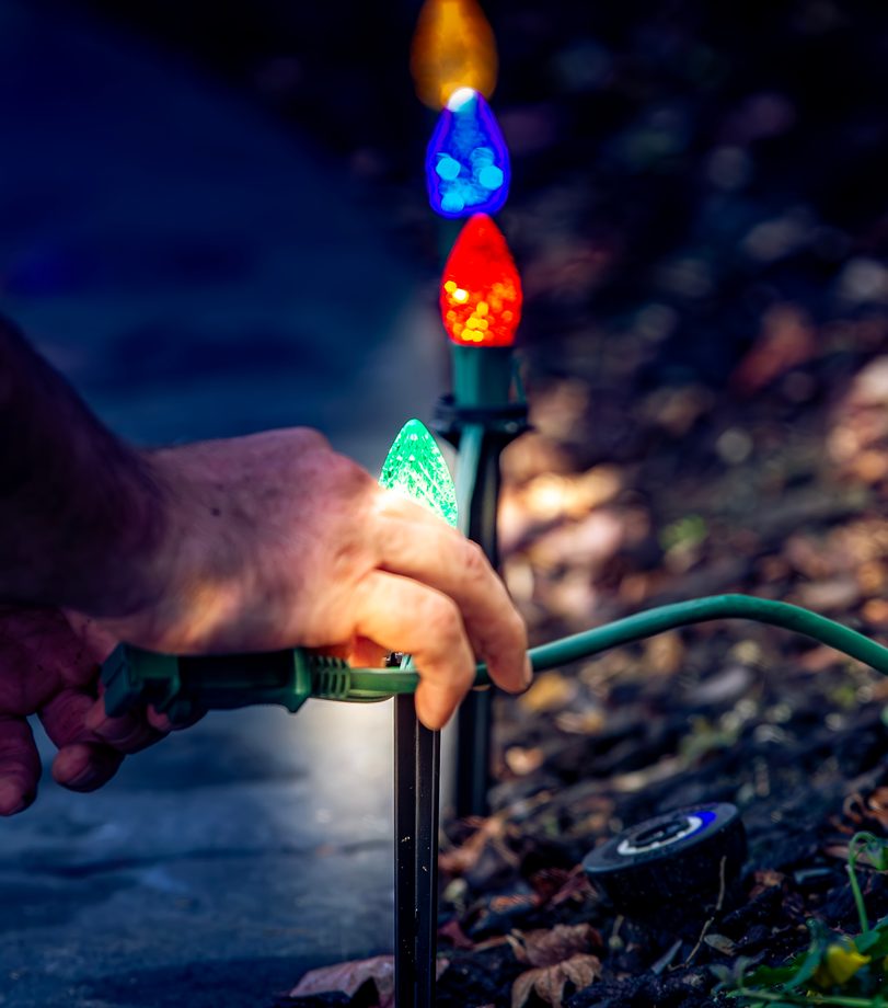 A hand pressing a coloured stake light into a border