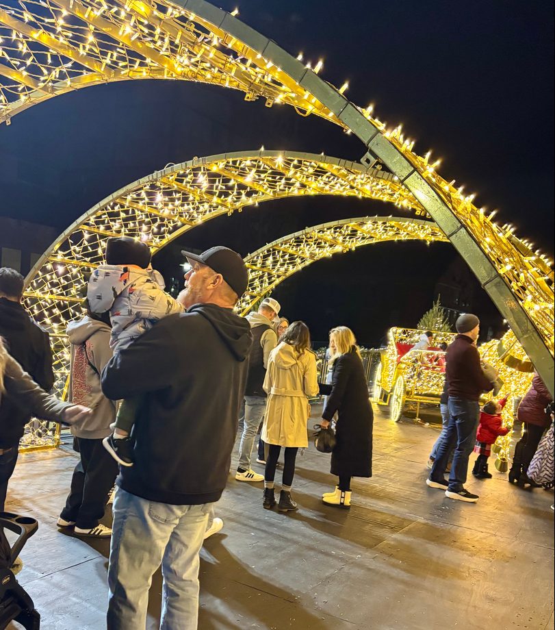 Families walking under lit arches at a town display
